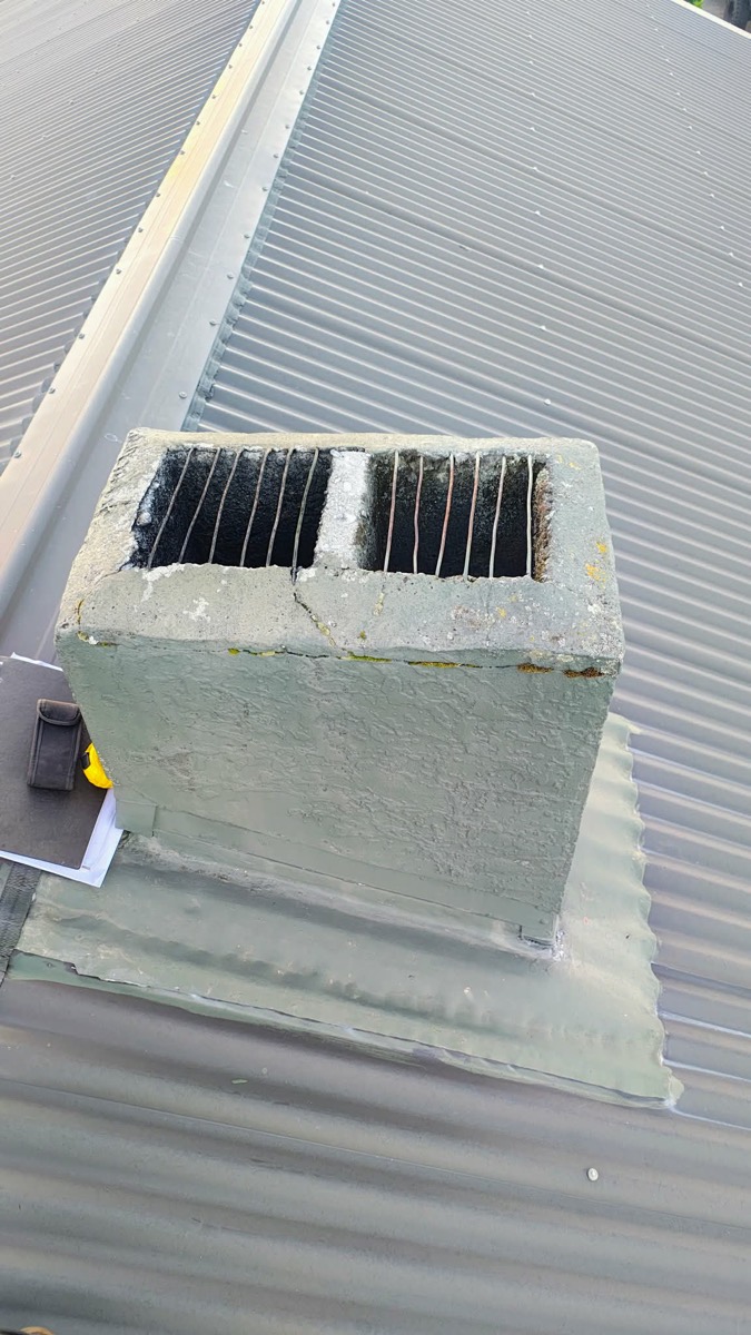 An open, uncapped concrete chimney on a metal roof — before Premium Fires