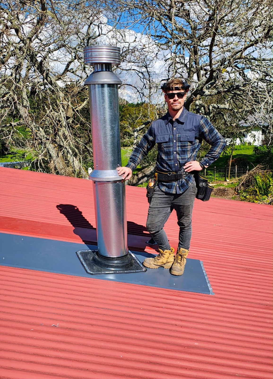Luke, owner-operator of Premium Fires, beside a newly installed flue on a Northland roof